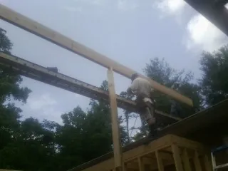 Carpenter setting a ridge beam over a new addition frame — Ice Dam Removal by Roofing Brothers in Riva