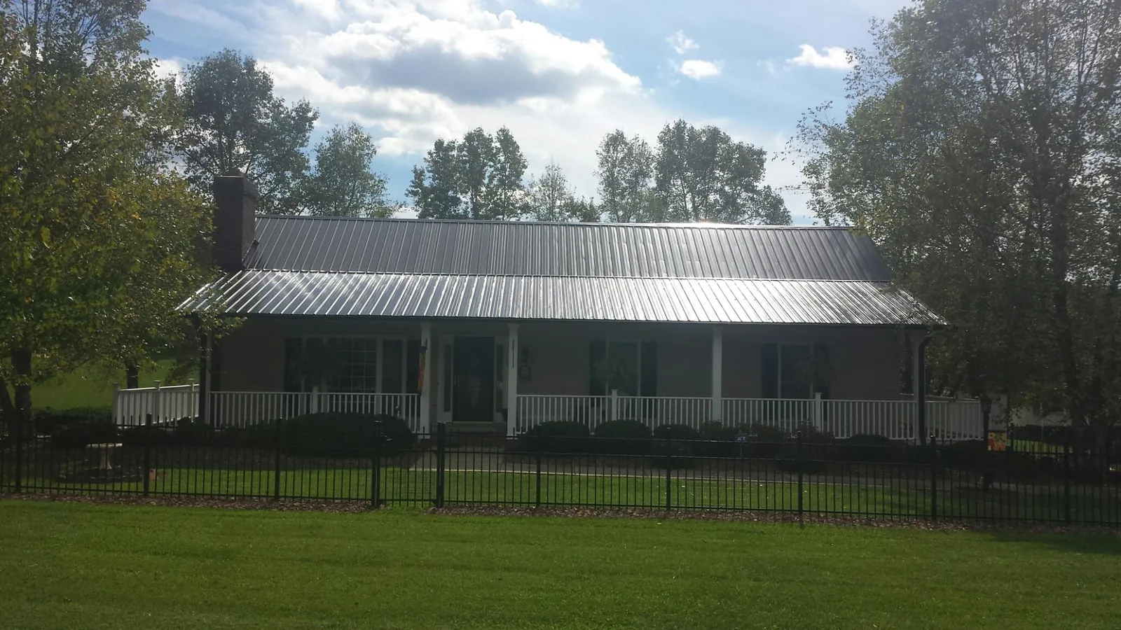 Gray metal roof on a brick ranch with a full width front porch — Gutter Guard Installation work by our crew in Riva