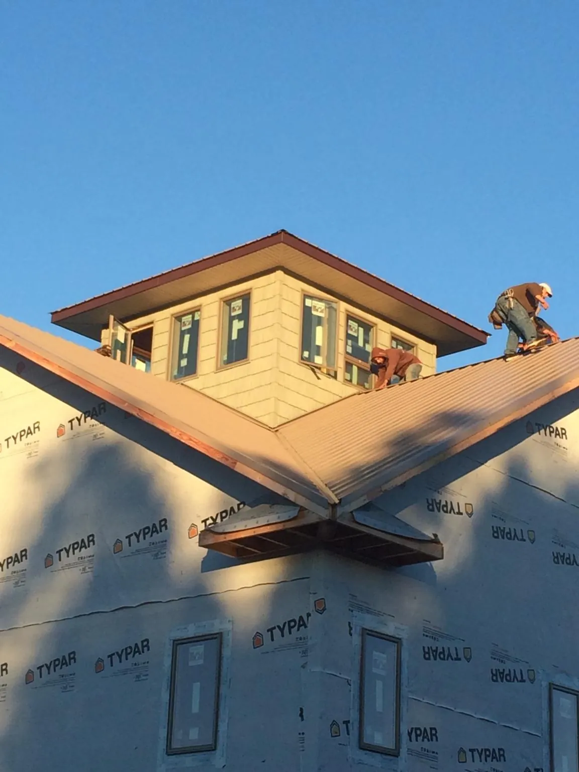 Roofers working around a rooftop cupola on a new metal roof at sunset — Roof Waterproofing in Riva by Roofing Brothers